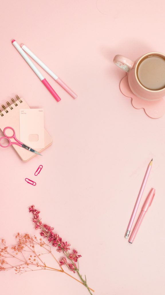 Aesthetic pink office flat lay featuring stationery and coffee.
